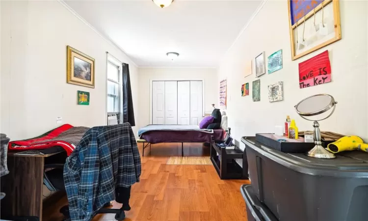 Bedroom featuring a closet, ornamental molding, and light hardwood / wood-style flooring