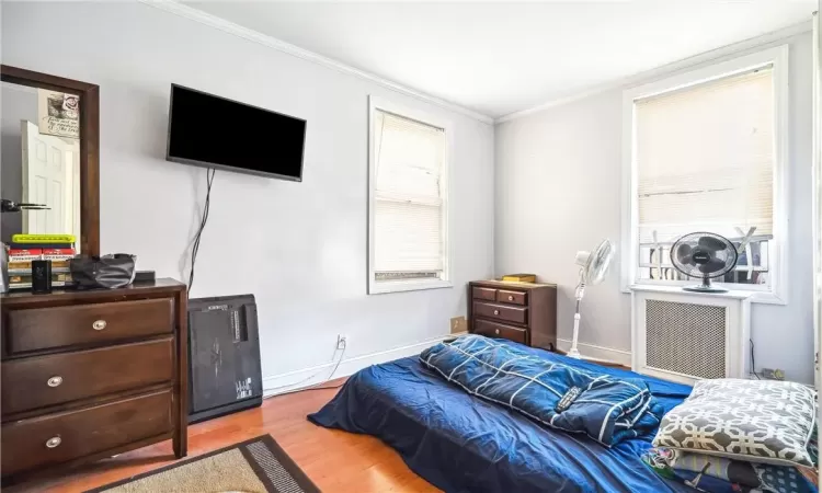 Bedroom with light hardwood / wood-style floors and crown molding