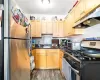 Kitchen with sink, backsplash, stainless steel appliances, light brown cabinets, and dark hardwood / wood-style floors