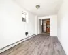 Empty room featuring cooling unit, crown molding, baseboard heating, and light wood-type flooring