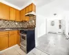 Kitchen featuring stainless steel gas range oven, a baseboard radiator, backsplash, light hardwood / wood-style flooring, and sink