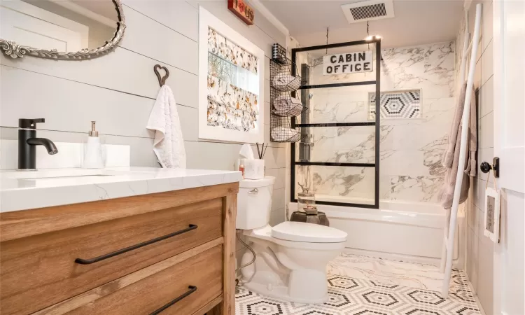 Full bathroom with tile patterned floors, vanity, tile walls, toilet, and tiled shower / bath