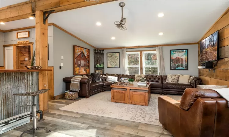 Living room featuring  ceiling with beams, crown molding, and light wood-type flooring