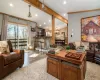 Living room featuring baseboard heating, crown molding, light hardwood / wood-style flooring, a notable chandelier, and vaulted ceiling with beams