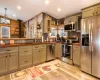 Kitchen with appliances with stainless steel finishes, wooden walls, sink, a wood stove, and lofted ceiling