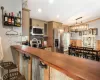 Live edge bar and counters, slate backsplash, stainless steel appliances, a chandelier, and hanging light fixtures