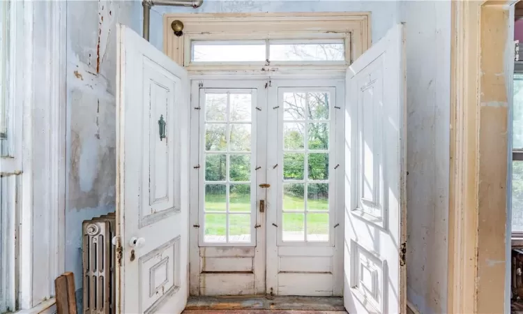 Doorway to outside with radiator heating unit and french doors