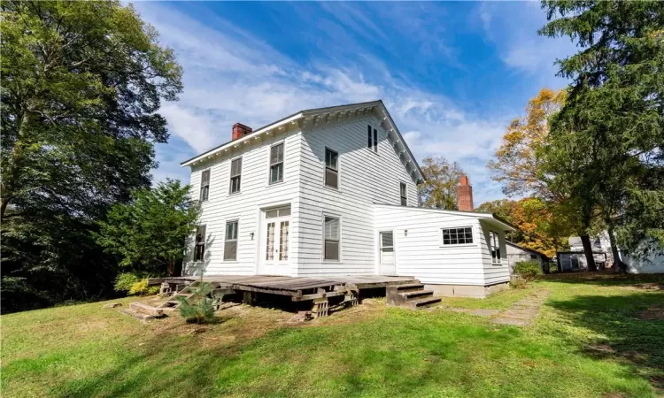 Back of house with a lawn and a deck