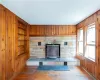 Unfurnished living room featuring built in shelves, wooden walls, dark hardwood / wood-style flooring, and a wood stove