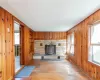 Unfurnished living room with a wood stove, light wood-type flooring, wood walls, and a healthy amount of sunlight