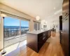 Kitchen with oversized island, pendant lighting, solid wood cabinetry, exhaust hood.