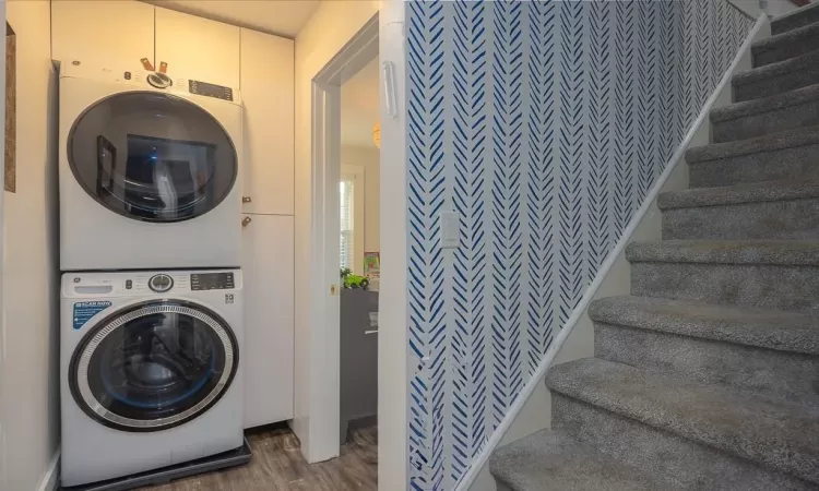 Laundry room featuring cabinets, dark hardwood / wood-style floors, and stacked washer and clothes dryer