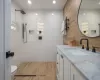 Bathroom featuring tile walls, wood-type flooring, tiled shower, vanity, and toilet