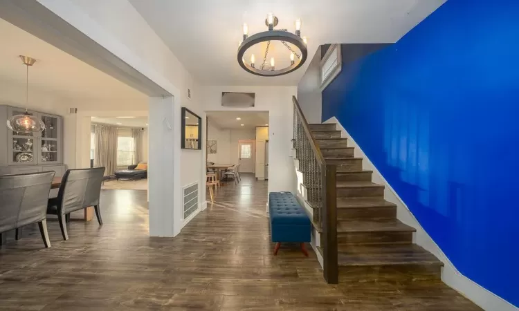 Staircase with wood-type flooring and an inviting chandelier