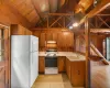 Kitchen with vaulted ceiling with beams, wood walls, and white appliances