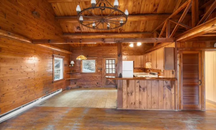 Kitchen with hardwood / wood-style floors, white fridge, wood walls, and kitchen peninsula