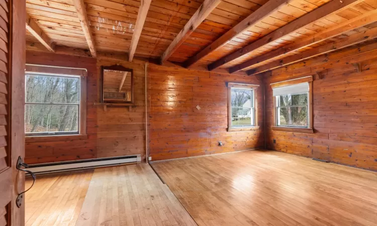 Empty room with light wood-type flooring, a wealth of natural light, and a baseboard heating unit