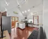 Kitchen with white cabinetry, hanging light fixtures, high vaulted ceiling, a kitchen island, and appliances with stainless steel finishes