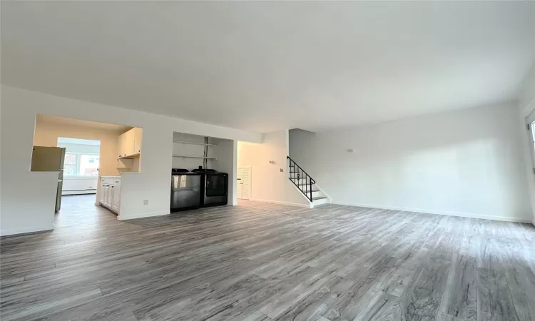 Unfurnished living room with light wood-type flooring and baseboard heating