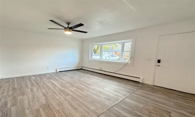 Spare room featuring ceiling fan, a baseboard heating unit, and light wood-type flooring