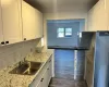 Kitchen featuring dark wood-type flooring, sink, decorative backsplash, a baseboard radiator, and white cabinetry