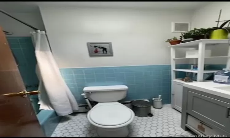 Bathroom with curtained shower, toilet, and tile walls