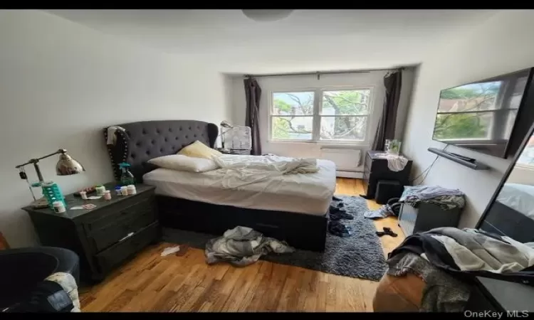 Bedroom featuring a baseboard heating unit and light hardwood / wood-style flooring