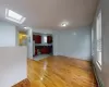 Unfurnished living room with a skylight, sink, light hardwood / wood-style floors, and a baseboard heating unit