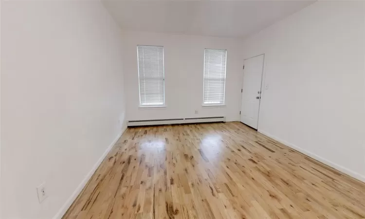 Unfurnished room featuring light hardwood / wood-style flooring and a baseboard heating unit