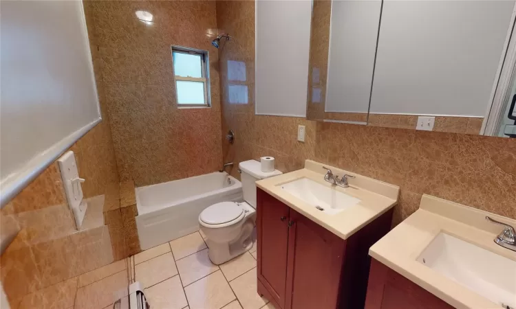 Full bathroom with vanity, tile walls, tile patterned flooring, toilet, and tiled shower / bath