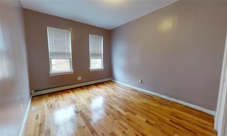 Empty room with baseboard heating and light hardwood / wood-style floors