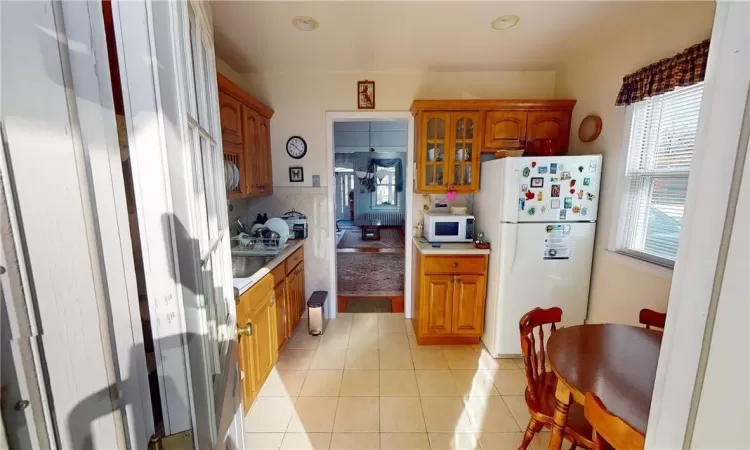 Kitchen featuring white appliances, light tile patterned floors, and decorative backsplash