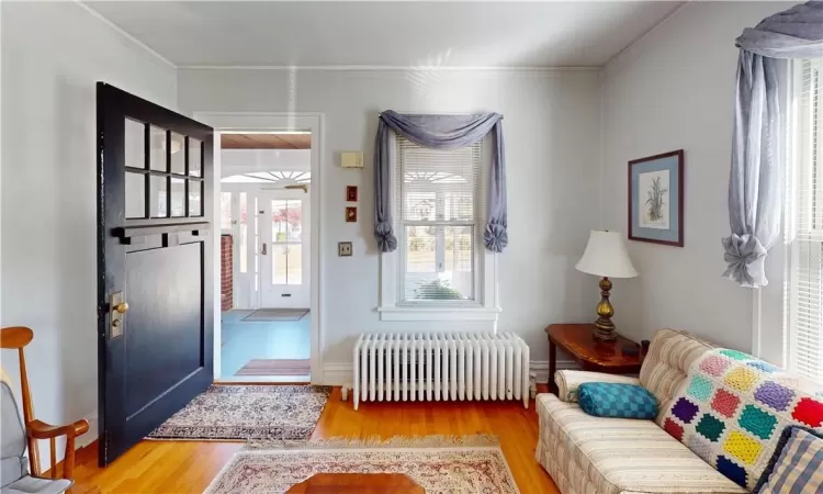 Entryway with hardwood / wood-style floors, radiator heating unit, and ornamental molding