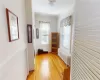 Hall with radiator, light wood-type flooring, a healthy amount of sunlight, and crown molding