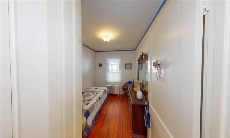 Bedroom featuring radiator, wood-type flooring, and crown molding