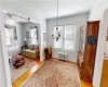 Living area with radiator heating unit, light hardwood / wood-style flooring, and a notable chandelier