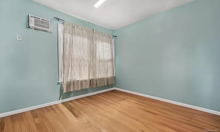 Empty room with hardwood / wood-style floors and a wall mounted AC