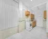 Kitchen with white range with electric cooktop, sink, light tile patterned floors, and tile walls