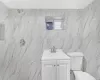 Bathroom with a shower, vanity, toilet, and tile walls