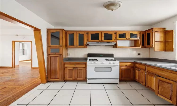 Kitchen with sink, gas range gas stove, decorative backsplash, and light tile patterned floors