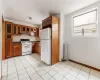 Kitchen featuring light tile patterned floors, radiator, decorative backsplash, and white appliances