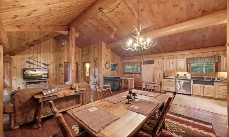 Dining area featuring hardwood / wood-style floors, wooden walls, a chandelier, and wooden ceiling