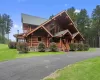 Log-style house with a porch and a front lawn