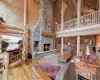 Living room with wood-type flooring, rustic walls, wooden walls, a stone fireplace, and a towering ceiling