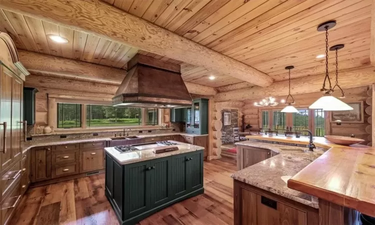 Kitchen featuring decorative light fixtures, dark hardwood / wood-style flooring, beam ceiling, log walls, and a kitchen island