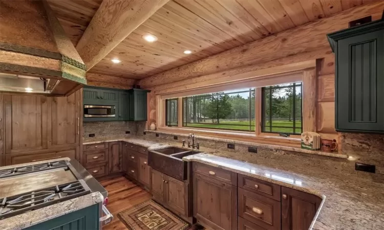 Kitchen featuring range, tasteful backsplash, hardwood / wood-style floors, sink, and custom range hood