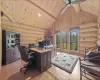 Office area with light hardwood / wood-style flooring, rustic walls, wood ceiling, ceiling fan, and high vaulted ceiling