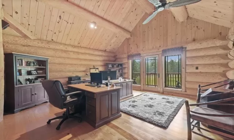 Office area with light hardwood / wood-style flooring, rustic walls, wood ceiling, ceiling fan, and high vaulted ceiling