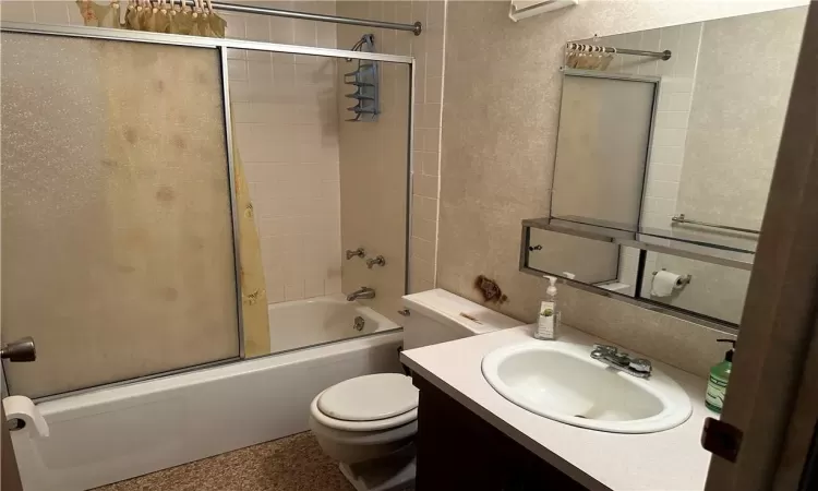 Full bathroom featuring vanity, toilet, and bath / shower combo with glass door