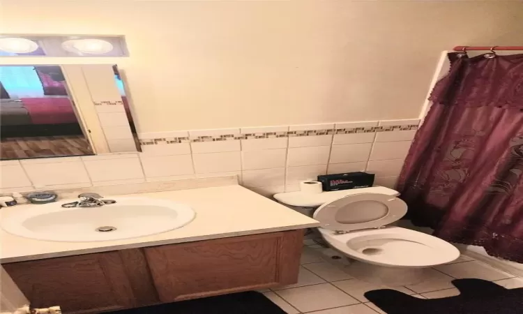 Bathroom with tile walls, tasteful backsplash, toilet, tile flooring, and large vanity